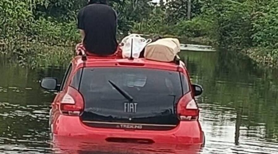 Motorista sobe em teto de carro após ficar ilhado durante enchente no litoral de SP